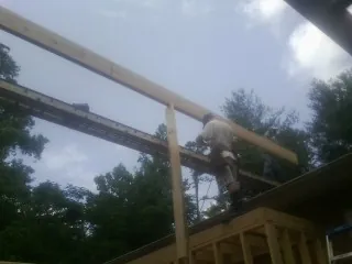 Carpenter setting a ridge beam over a new addition frame — Ice Dam Removal by Roofing Brothers in Bentley