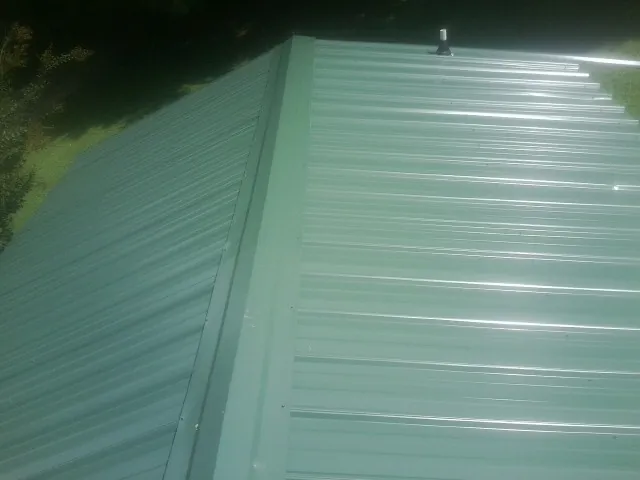 New green metal panels meeting at the ridge of a roof — Flat Roof Repair work by our crew in Bentley