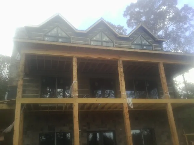 Dormers and porch framing on a large log home under construction — Roof Coating work by our crew in Bentley