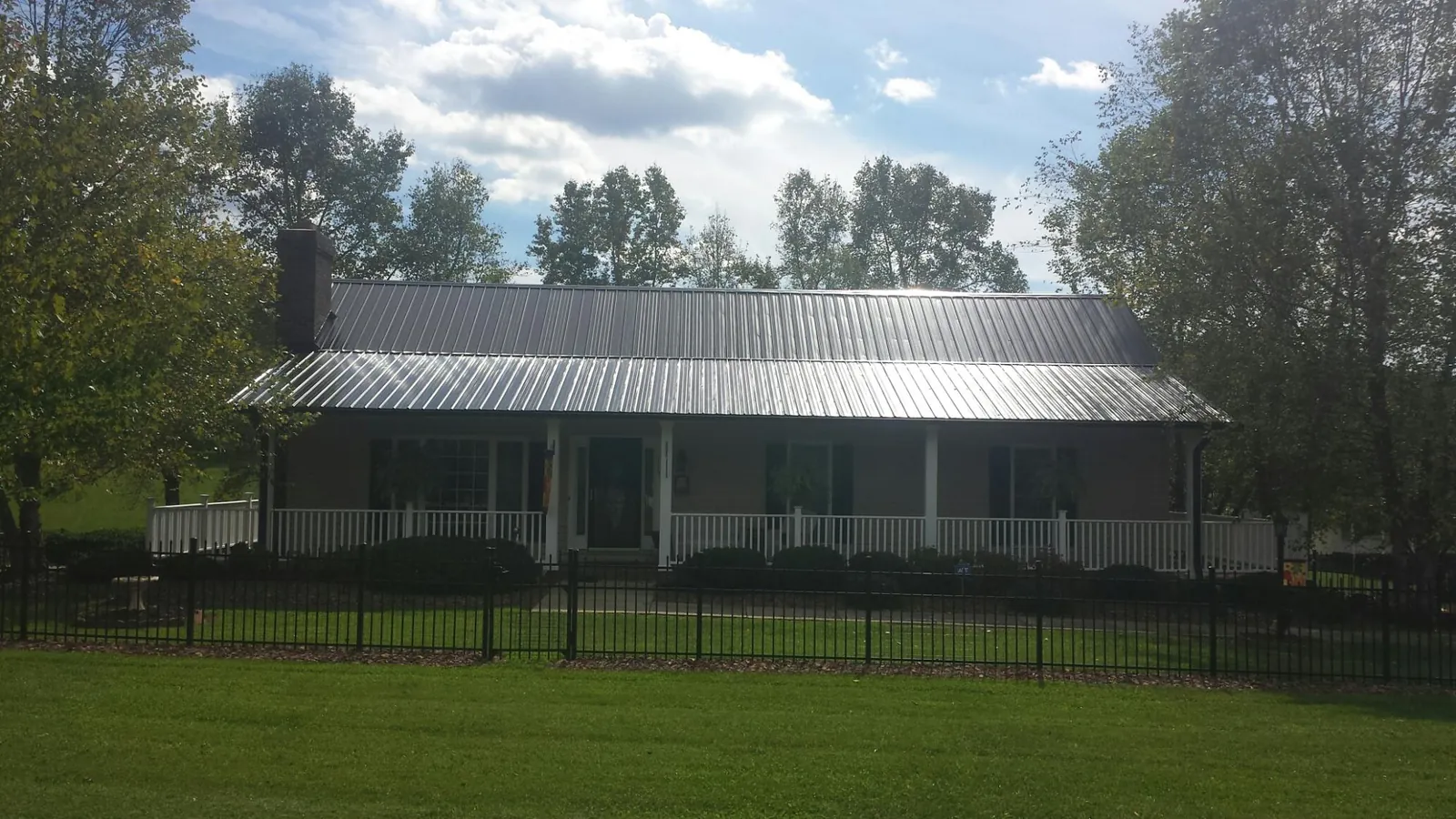 Gray metal roof on a brick ranch with a full width front porch — Gutter Guard Installation work by our crew in Bentley