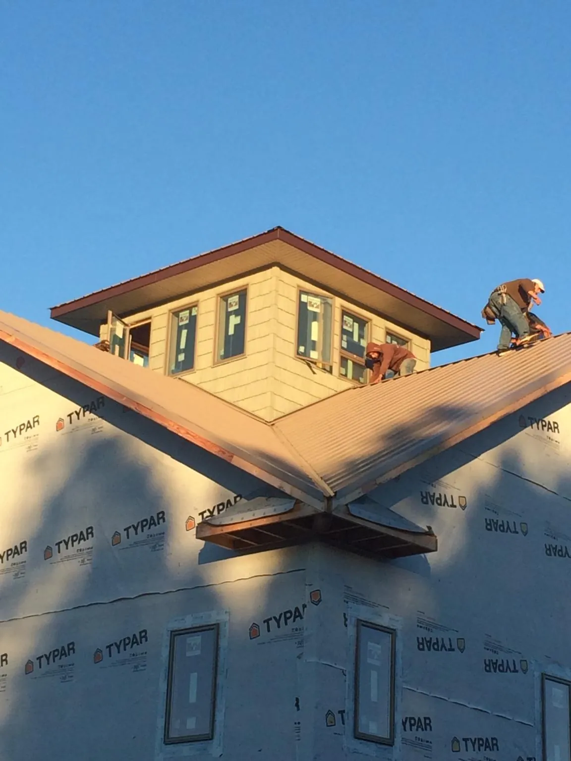 Roofers working around a rooftop cupola on a new metal roof at sunset — Roof Waterproofing in Bentley by Roofing Brothers